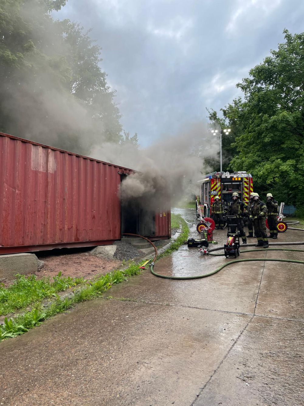 Rauchende Container neben einem Feuerwehrauto