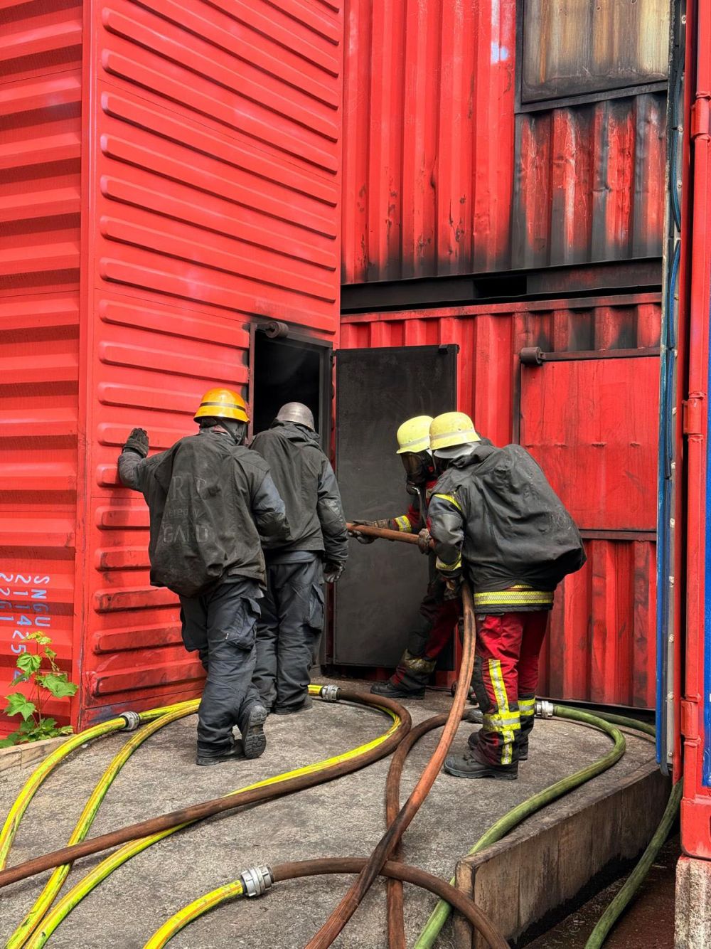 Voll ausgerüstete Feuerwehrleute am Container Eingang