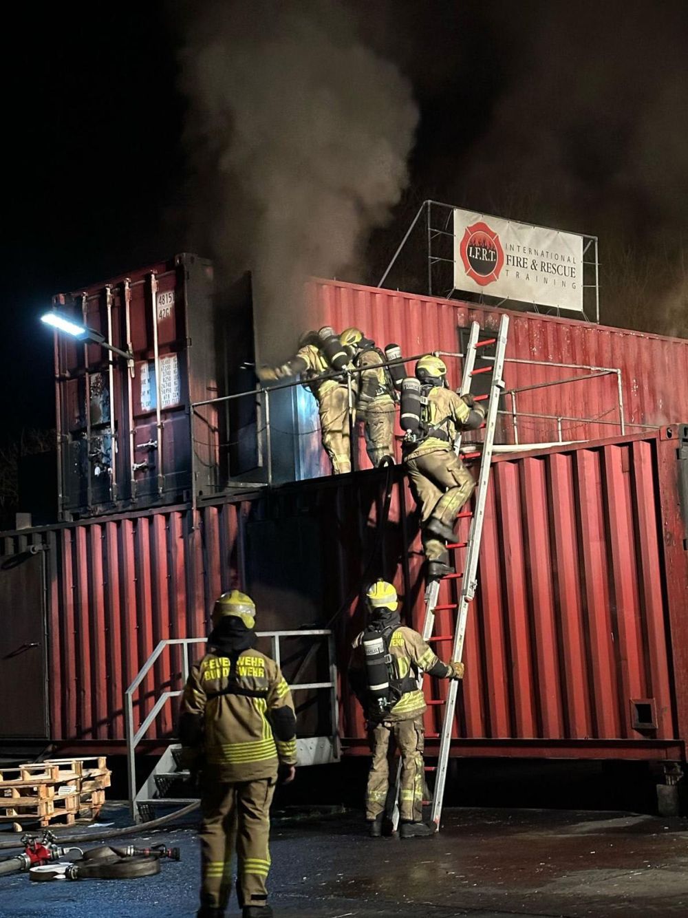 Feuerwehrleute auf rauchenden Containern