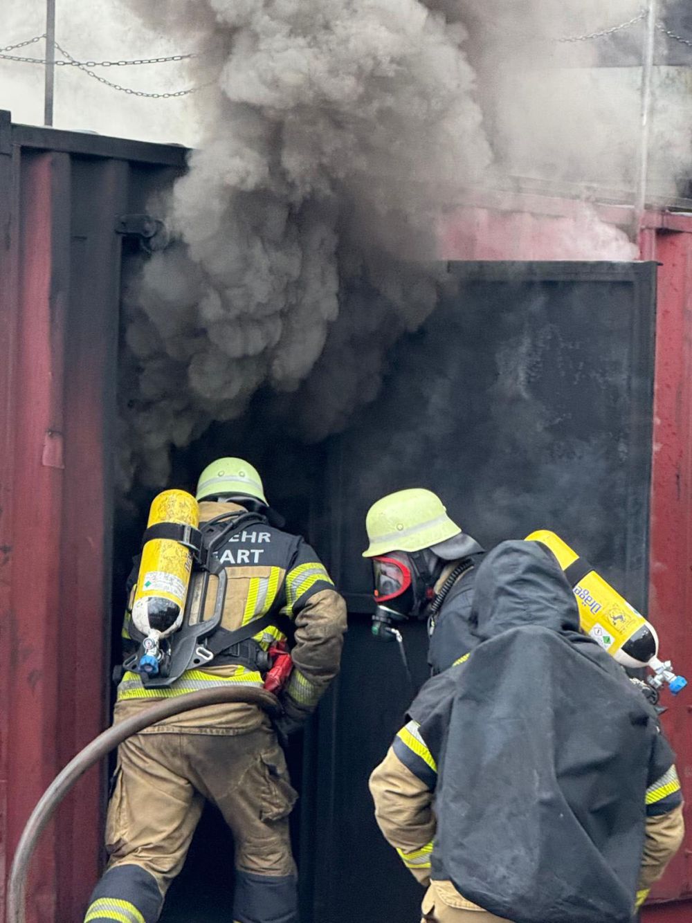 Dunkler Rauch aus einem Container, in den Feuerwehrleute gehen